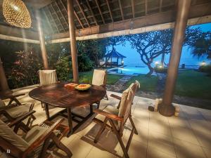 a table and chairs on a patio with a view of the ocean at Villa Seaview- tranquil 3BR, beachfront, private pool in Bukti
