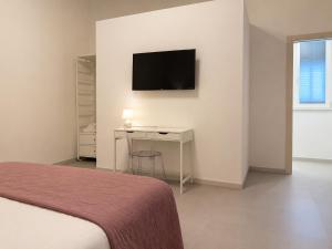 a bedroom with a bed and a desk and a television at Liolà Rooms in Terrasini