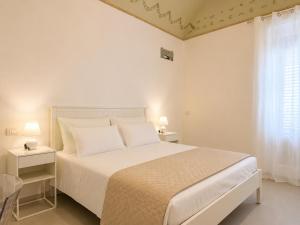 a white bedroom with a bed and a window at Liolà Rooms in Terrasini