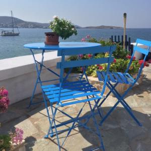 a blue table and a blue chair sitting next to the water at Captain Bay's Unique Heritage Home in Finikas +6 photos