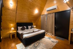 a bedroom with a bed in a wooden room at The Arks Baagh Villas in Rāmnagar +10 photos
