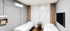 a room with two white beds and a marble wall at Neela Homestay in Labuan