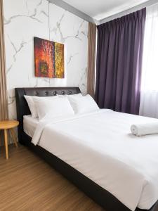 a bedroom with a large bed with white sheets at Neela Homestay in Labuan