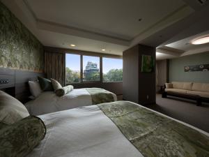 熊本市にあるKKRホテル熊本のベッド2台とソファが備わるホテルルームです。