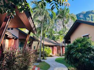 a walkway between two buildings with palm trees at Aonang Hill Krabi-SHA Extra Plus in Ao Nang Beach
