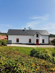 a white house with a red door at Maggies Cottage in Manorhamilton