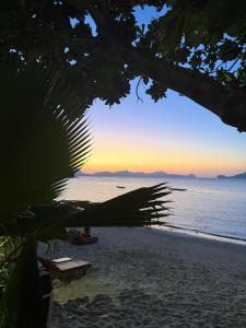 a view of a beach with a sunset in the background at Bahay El Nido in El Nido