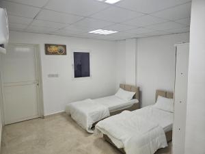 two beds in a room with white walls at غرف شباب عوقد in Salalah