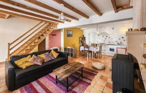 a living room with a black couch and a kitchen at Harmant Gîte Au Calme in Saint-Maigrin
