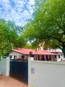 a white house with a gate and a fence at Lion Isle Residence in Anuradhapura