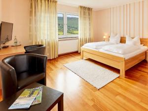 a bedroom with a bed and a desk and a chair at Püttmanns Dorfhotel in Olpe +22 photos