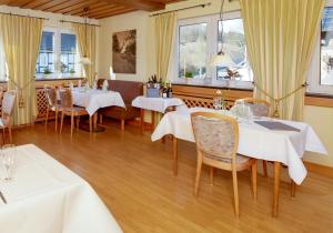 a restaurant with white tables and chairs and windows at Püttmanns Dorfhotel in Olpe