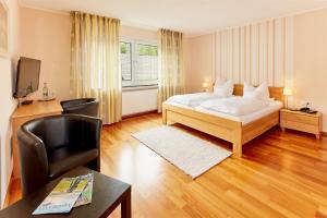 a bedroom with a bed and a desk and a chair at Püttmanns Dorfhotel in Olpe