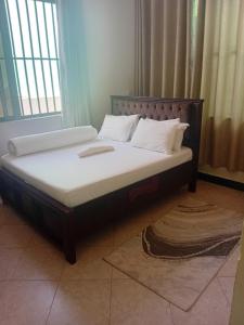 a bed with a wooden frame and white pillows at Ponte Vedra Lodge in Mwanza