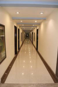 a long hallway in a building with white floors at Hotel centrum in Roorkee