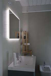 a white bathroom with a sink and a mirror at Cementina 56 in Noci