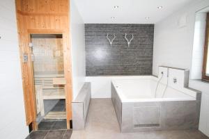 a bath tub in a bathroom with a brick wall at Chalet Hochkrimml 49 in Nothdorf +27 photos