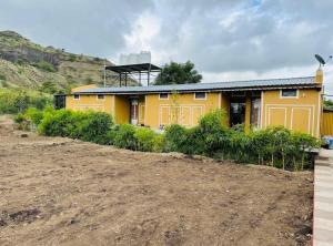 a yellow house with a dirt road in front of it at Ashoka Resort in Wai