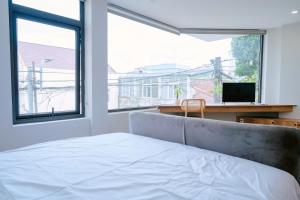 a bedroom with a bed and a desk and windows at NGỌN HẢI ĐĂNG Hotel in Dong Hoi