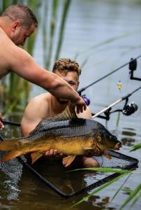 a man holding a large fish in the water at Malownicze Owieczki in Owieczki