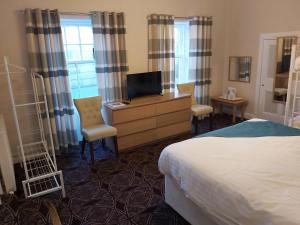 a hotel room with a bed and a desk with a television at The Strathearn Hotel in Fife