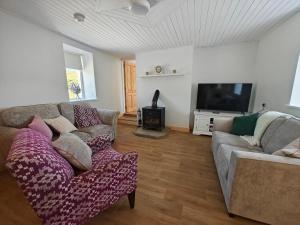 a living room with two couches and a flat screen tv at Maggies Cottage in Manorhamilton