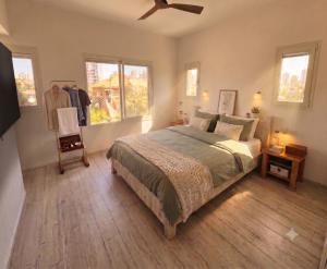 a bedroom with a bed and a chair and windows at Gador Sea View in H̱adera