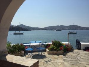 a patio with a table and chairs next to the water at Captain Bay's Unique Heritage Home in Finikas
