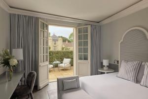 a bedroom with a white bed and a balcony at COMO Cordeillan-Bages in Pauillac