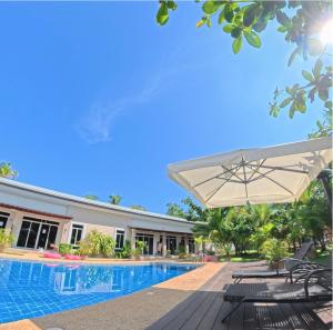 a pool with chairs and an umbrella next to a building at The Retreat in Panglao Island