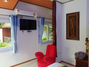 sala de estar con silla roja y TV de pantalla plana en Rerawadi Resort, en Khun Han