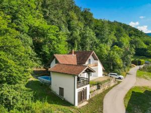 a small white house with a red roof next to a road at Vila Vidovic Drina in Bajina Bašta