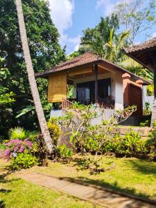 a house with a garden and a palm tree at Pondok Alam Bukit in Tirtagangga