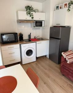a small kitchen with a washer and a refrigerator at Appartement La Parenthèse Verte - Capvern in Capvern