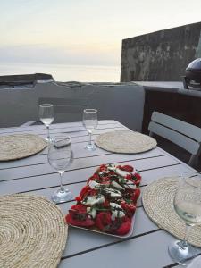 ein Tisch mit einem Teller Essen und Weingläsern in der Unterkunft Cap Hélios, vue mer à couper le souffle à Centuri in Morsiglia