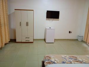a room with a refrigerator and a tv on a wall at Abuesi Beach Resort in Sekondi-Takoradi