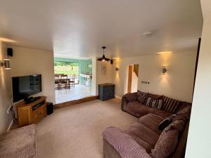 a living room with a couch and a tv at Woodland Forge - The Stables in Over Whitacre