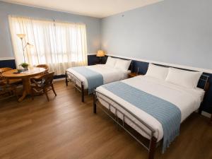 ein Hotelzimmer mit zwei Betten, einem Tisch und einem Fenster in der Unterkunft Richca Heritage Hotel in Chilliwack