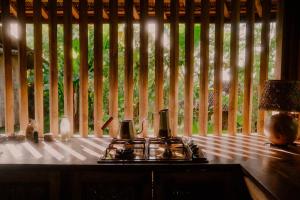 a room with a table with a stove and a window at Cosy Cottage Living Harmoniously in Tabanan