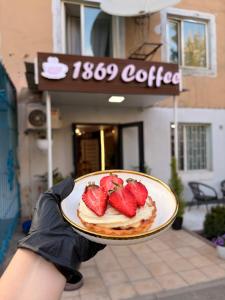a person holding a plate of food with strawberries on it at Hostel 1869 in Karakol