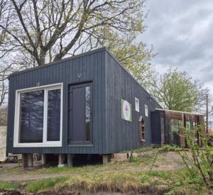 a black house with a window on a field at Zilvitis in Karklė