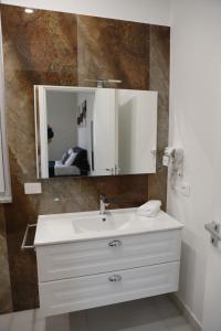 a bathroom with a white sink and a mirror at Alcenide Aparthotel in Villa San Giovanni