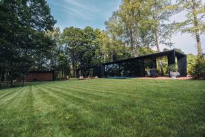 a black house in a field with a large yard at Stars Resort Sigulda in Sigulda