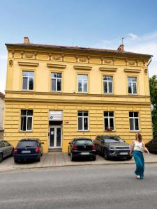 a woman walking in front of a yellow building at Samaya Apartment in Litoměřice