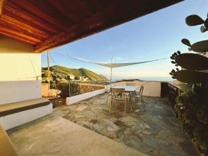 eine Terrasse mit Tisch und Stühlen auf einem Balkon in der Unterkunft Cap Hélios, vue mer à couper le souffle à Centuri in Morsiglia