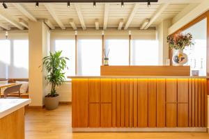 an office lobby with a wooden reception counter with plants at Guest House Aura - Lumys Fiumicino in Fiumicino