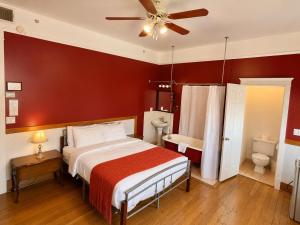 ein Schlafzimmer mit einem Bett und einer roten Wand in der Unterkunft Richca Heritage Hotel in Chilliwack