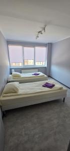 two beds in a room with two windows at LionEstateHostel in Liepāja +2 photos