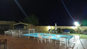 a pool at night with tables and chairs next to it at Hotel Los Barruecos in Malpartida de Cáceres