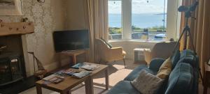 a living room with a blue couch and a tv at Douglas Park Guest House in Dunoon